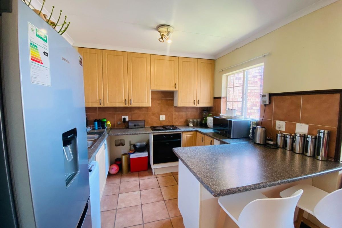 A functional kitchen featuring light wood cabinetry, granite-look countertops, tiled backsplash, and a breakfast bar peninsula.