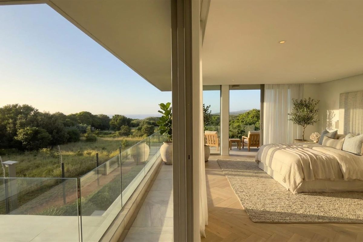 Spacious bedroom featuring herringbone timber flooring and large sliding glass doors opening onto a private balcony with scenic landscape views.