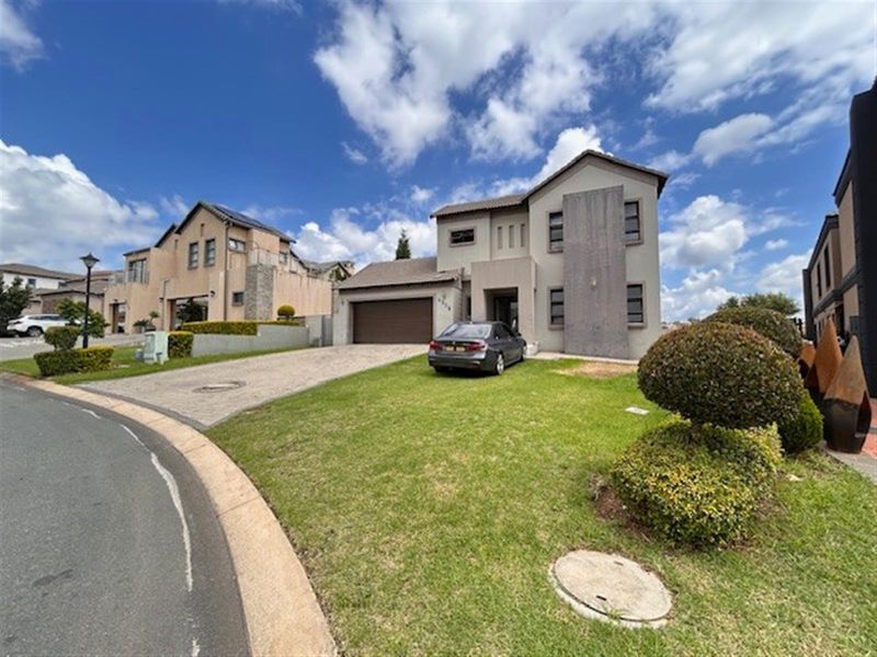 Front elevation of a modern two-story residential house featuring a paved driveway, double garage, and well-maintained front garden.