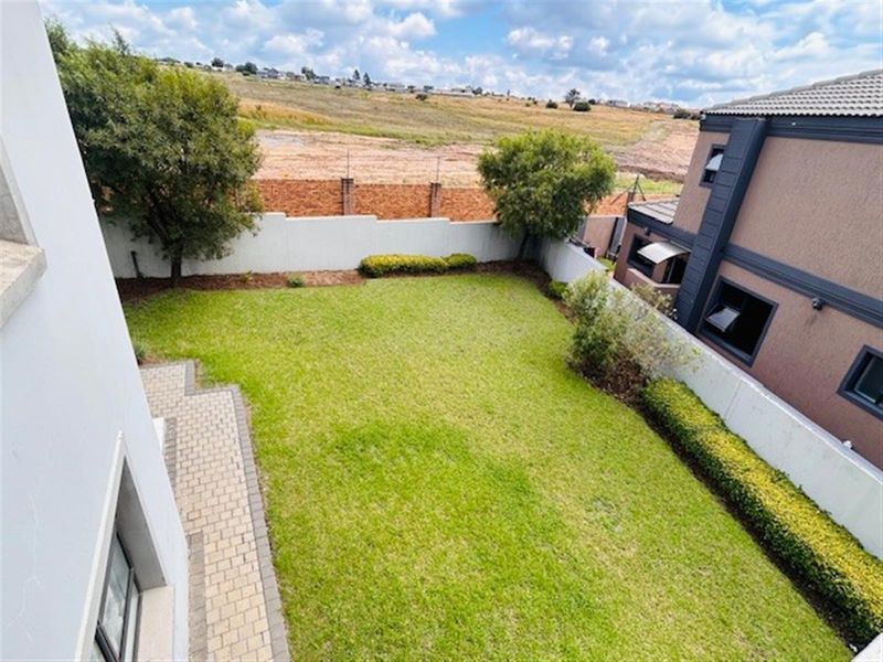 A well-maintained rear garden featuring a paved patio area, manicured lawn, and perimeter boundary walls, offering a private outdoor space.