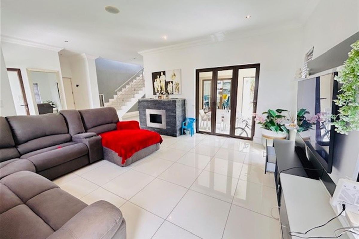 Spacious living room featuring large format floor tiles, a modern fireplace, and bi-fold doors providing seamless access to the outdoor area.