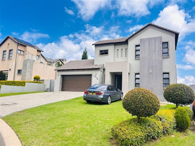 A modern two-story residential home featuring a tiled roof, paved driveway, double garage, and a well-maintained front garden.