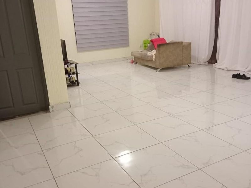 Spacious living area featuring modern marble-look porcelain floor tiles, neutral wall finishes, and large windows with roller blinds and curtain tracks.