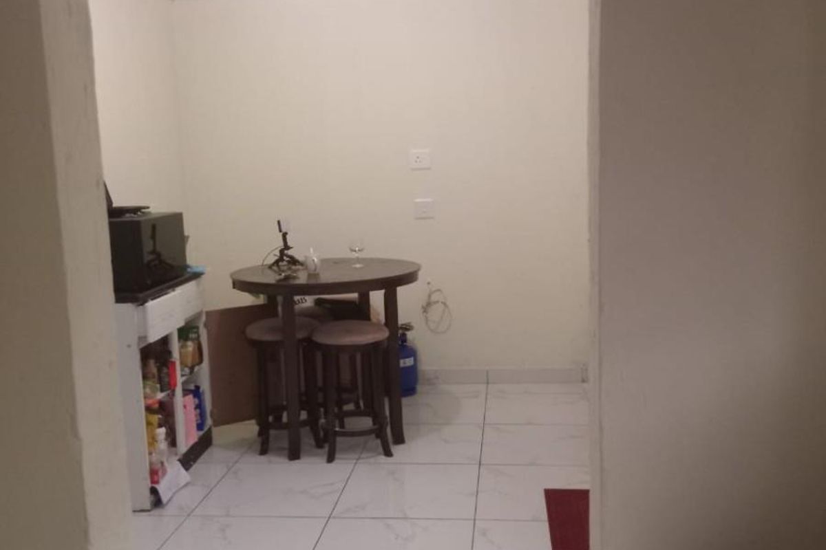 A functional kitchen area featuring tiled flooring and simple finishes, viewed from an adjacent utility space.