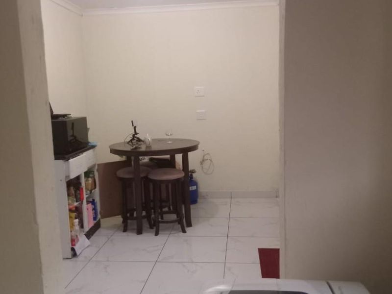 A functional kitchen area featuring tiled flooring and simple finishes, viewed from an adjacent utility space.