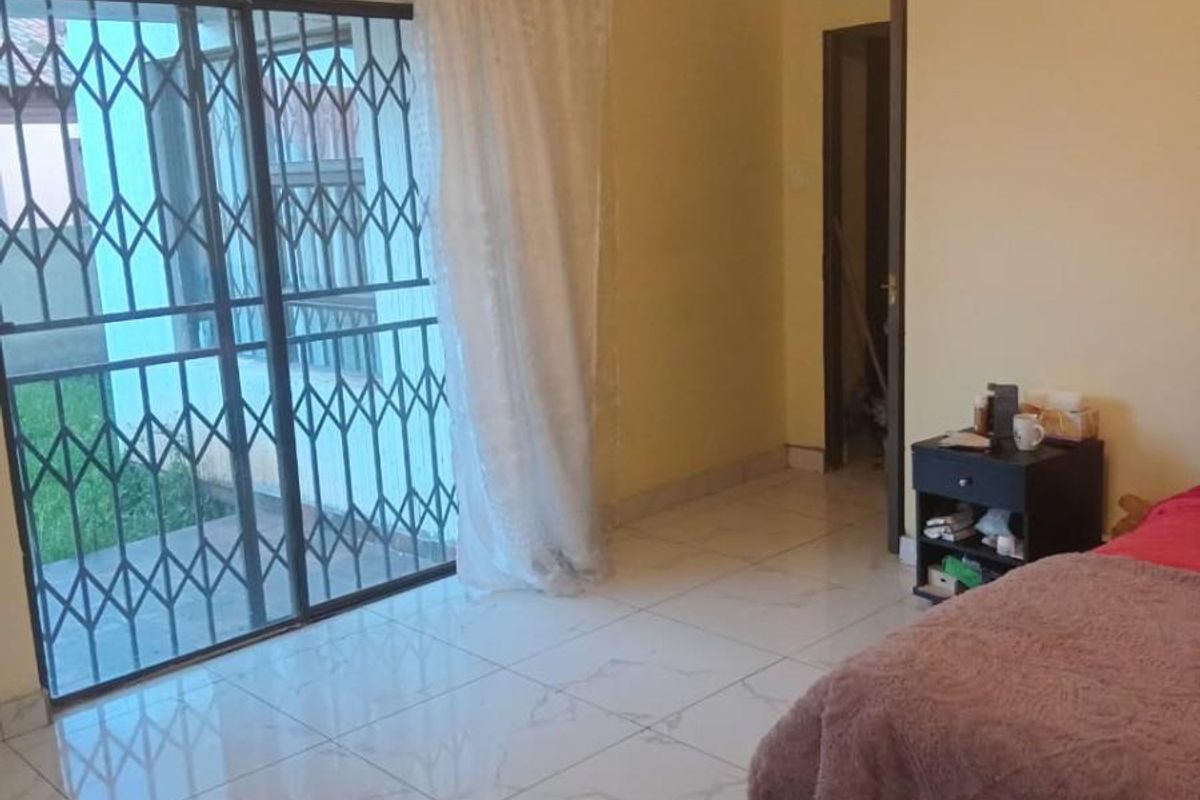 Bedroom featuring large sliding glass doors with security gate, tiled flooring, and neutral wall finishes.