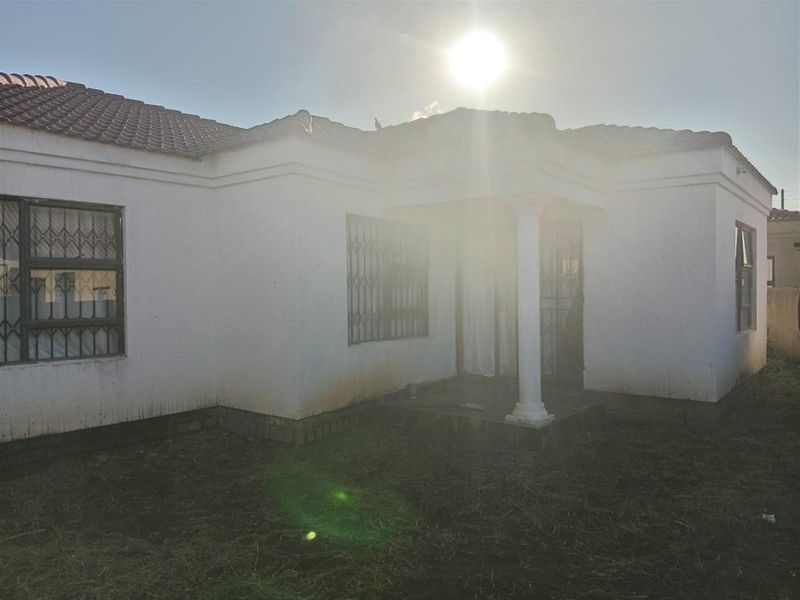 Front elevation of a single-story house featuring a tiled roof, security bars on windows, and a covered entrance porch with a structural column.