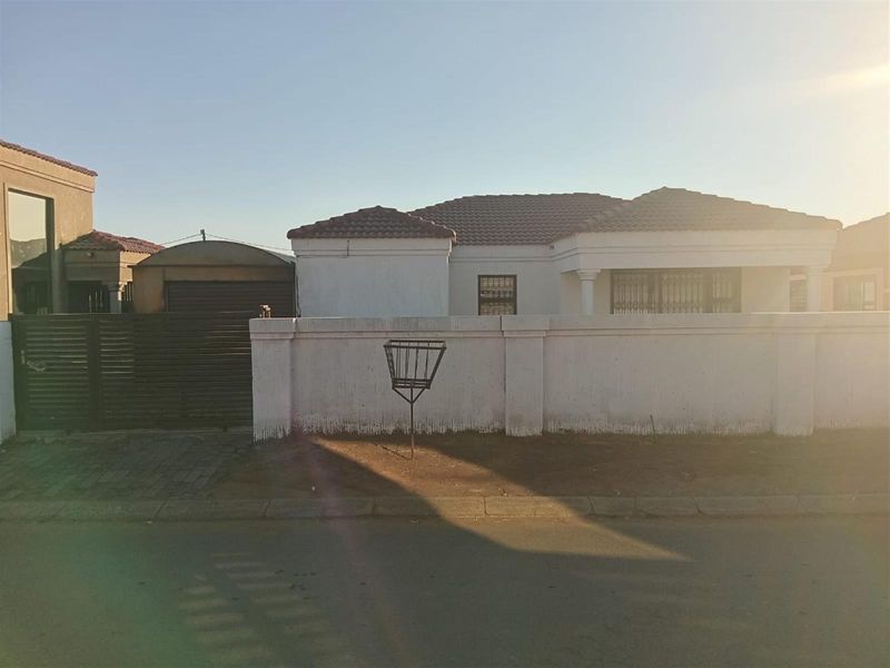Front exterior view of the house featuring a perimeter wall, tiled roof, and gated driveway access.