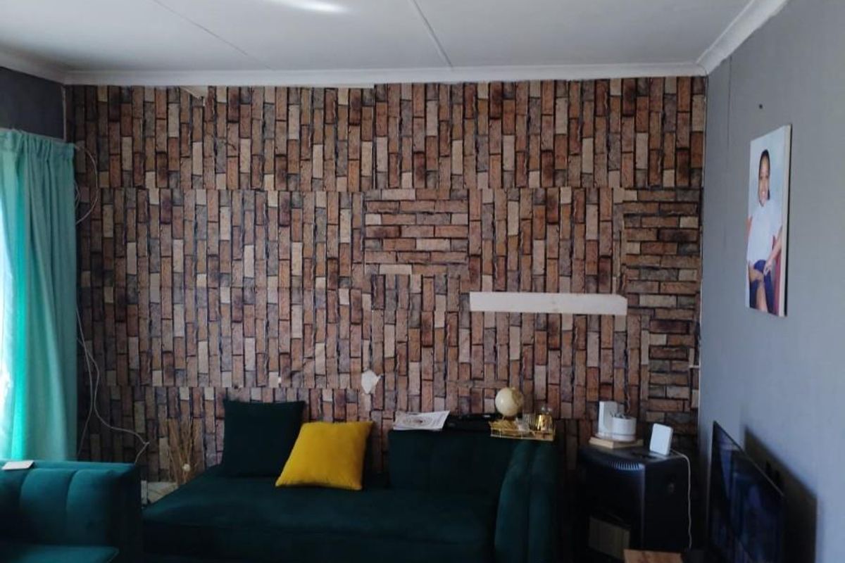 A living room featuring tiled flooring and a decorative brick-effect feature wall.