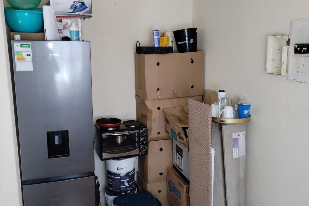 A utility or storage area featuring vinyl flooring and an exposed electrical distribution board, currently used for appliance and general storage.