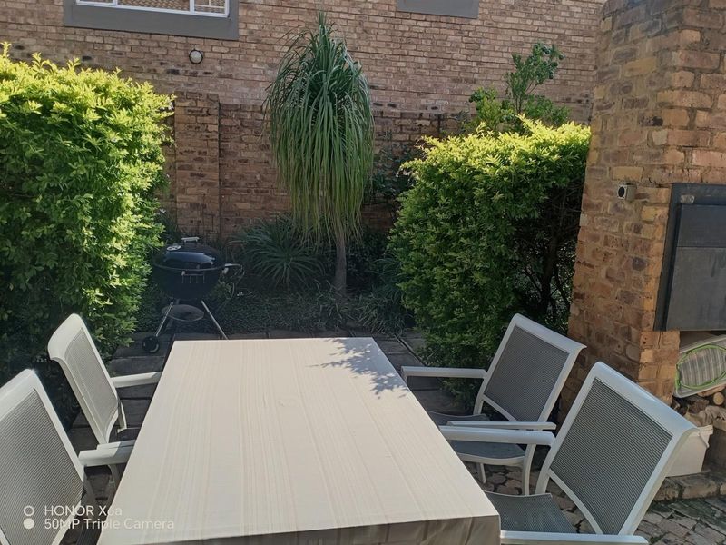 A private outdoor patio area featuring a brick boundary wall and a built-in braai, perfect for outdoor dining and entertaining.