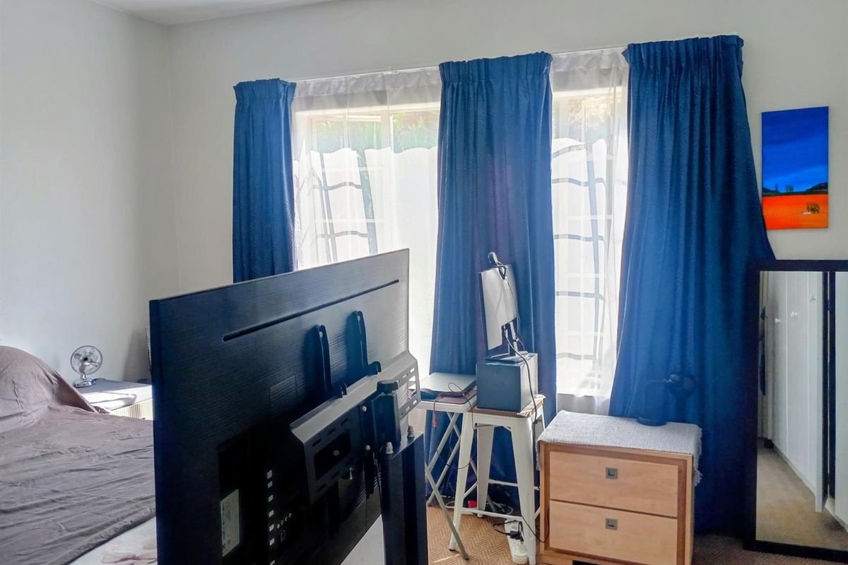 A bedroom featuring a window with curtains and a built-in wardrobe, providing a functional space for rest and storage.