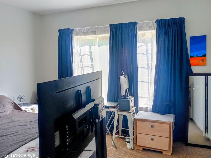 A bedroom featuring a window with curtains and a built-in wardrobe, providing a functional space for rest and storage.