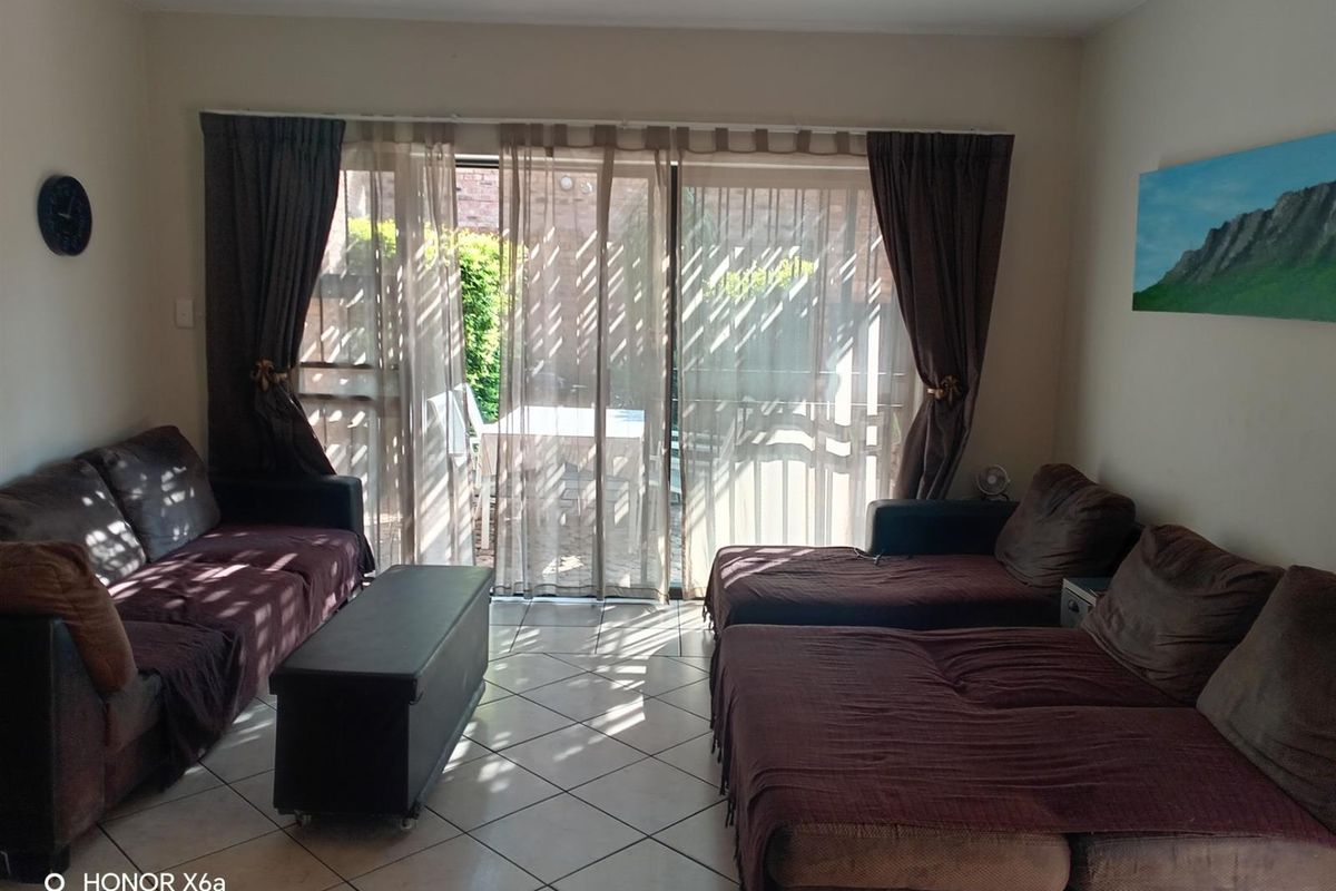 A living room featuring ceramic floor tiles and large sliding glass doors that provide access to the outdoor patio area.