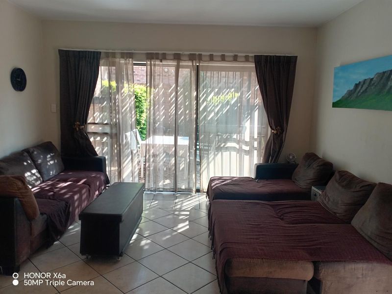 A living room featuring ceramic floor tiles and large sliding glass doors that provide access to the outdoor patio area.