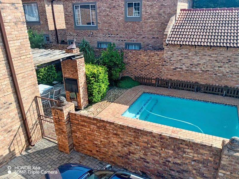 Rear courtyard featuring a private swimming pool, built-in braai area, and paved patio space enclosed by brick boundary walls.