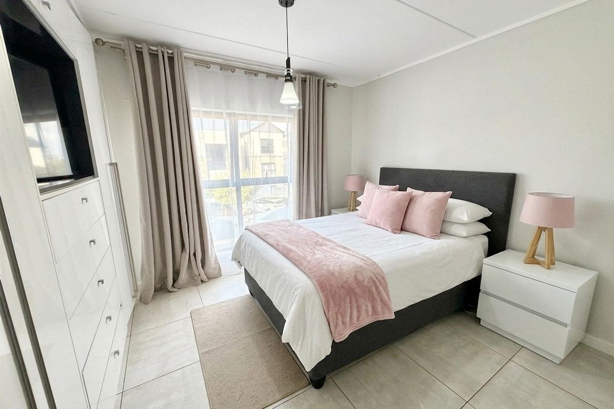A well-lit bedroom featuring tiled flooring, a built-in wardrobe, and large sliding glass doors providing natural light and access to the exterior.