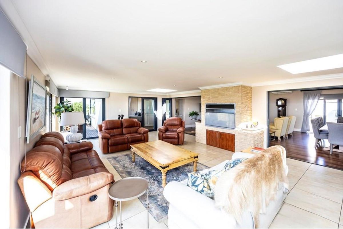 Spacious living room featuring a stone-clad fireplace, recessed lighting, skylights, and large sliding glass doors leading to an outdoor area.