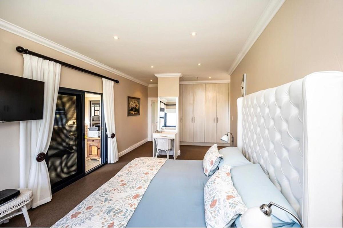 Spacious bedroom featuring built-in cupboards, a dedicated vanity area, recessed lighting, and sliding glass doors providing access to an outdoor space.