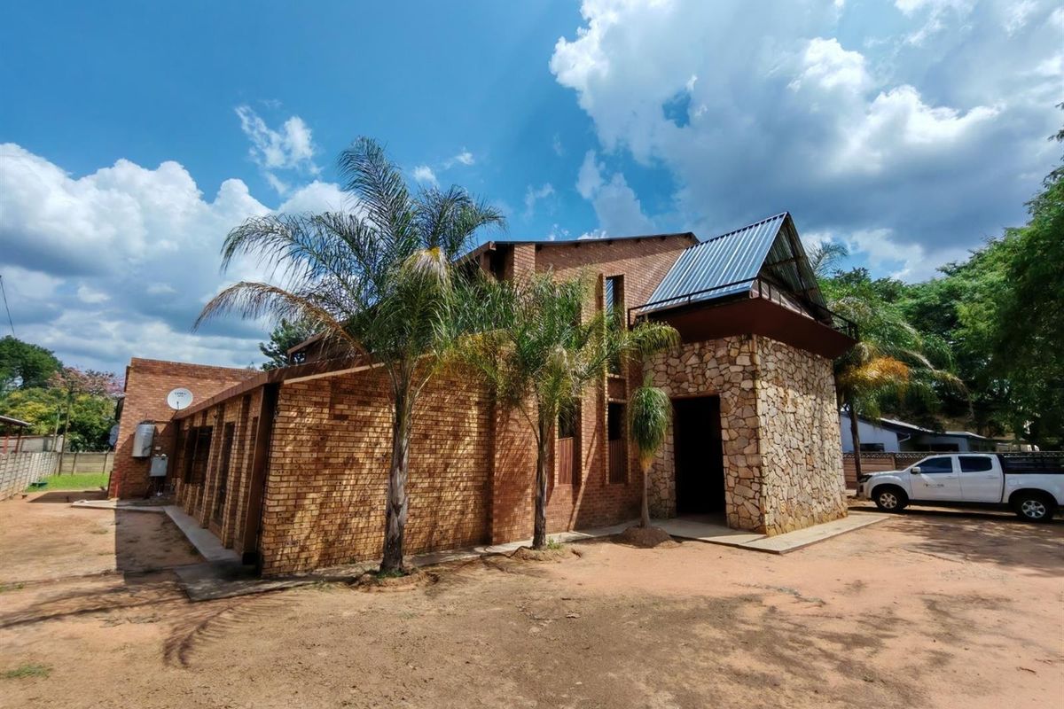Exterior view of a commercial building featuring face brick walls, stone cladding accents, and a metal roof structure.