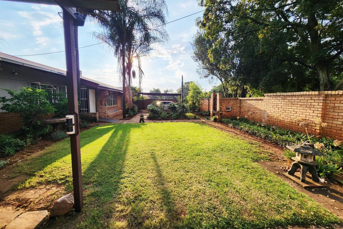 A spacious rear garden featuring a well-maintained lawn, perimeter brick walling, and established trees, providing a private outdoor area.