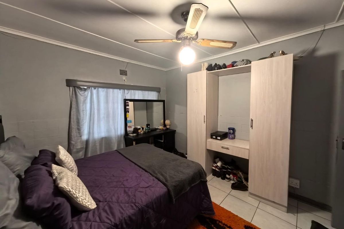 A bedroom featuring tiled flooring, a ceiling fan, and built-in wardrobe cabinetry.
