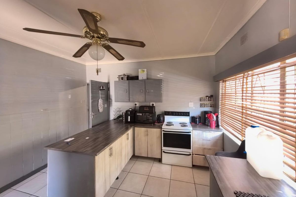Functional kitchen featuring light wood-tone cabinetry, dark laminate countertops, tiled flooring, and a freestanding electric stove.