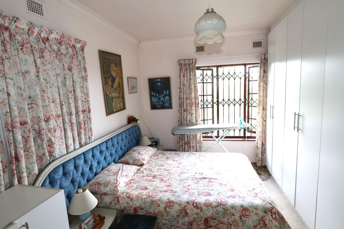 A bedroom featuring built-in floor-to-ceiling wardrobes, a window with security bars, and ceiling ventilation grilles.