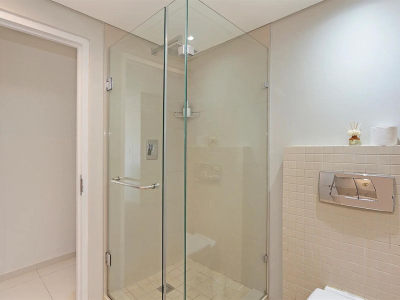Modern bathroom featuring a glass-enclosed shower with wall-mounted fixtures and a wall-mounted flush plate for the concealed cistern.