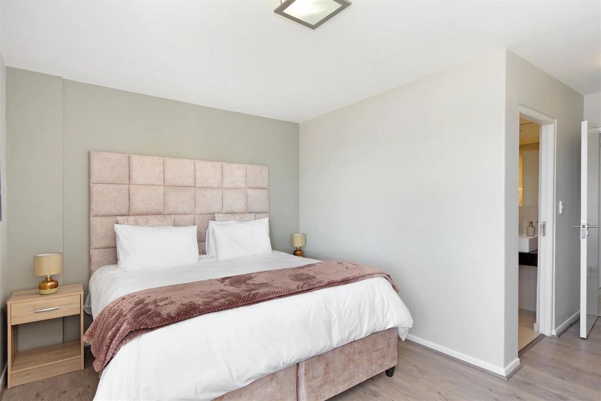 A well-maintained bedroom featuring neutral wall tones, laminate flooring, and direct access to an en-suite bathroom.