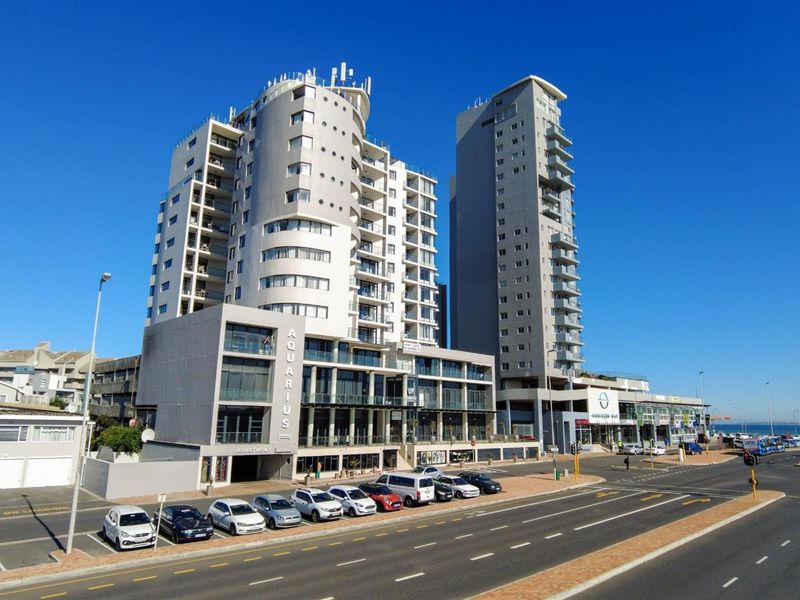 A high-angle exterior view of the Aquarius apartment complex, featuring modern multi-story architecture, private balconies, and convenient street-level parking.