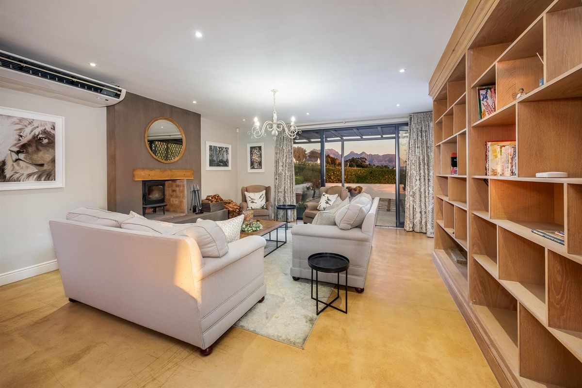 Spacious living room featuring a built-in fireplace, custom floor-to-ceiling wooden shelving, polished concrete flooring, and large sliding doors opening to a patio with mountain views.