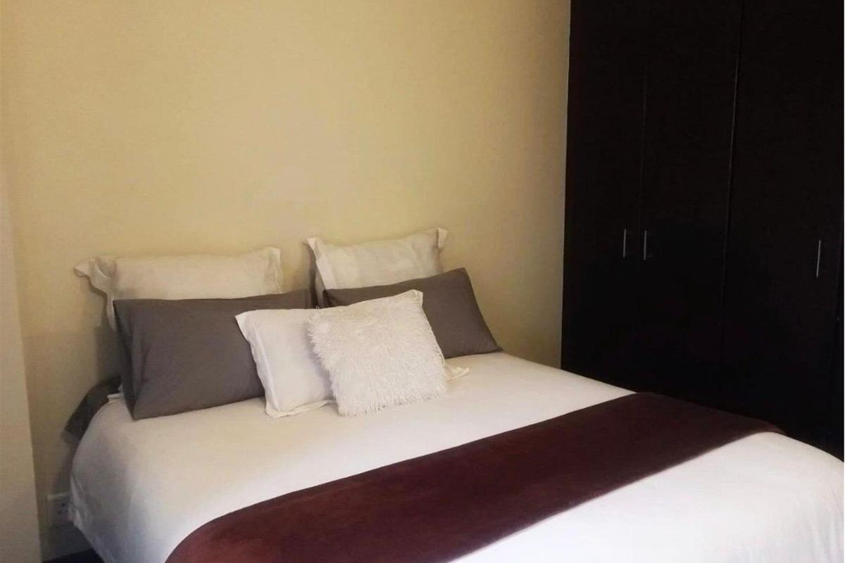 A bedroom featuring a dark built-in wardrobe and neutral wall finishes.