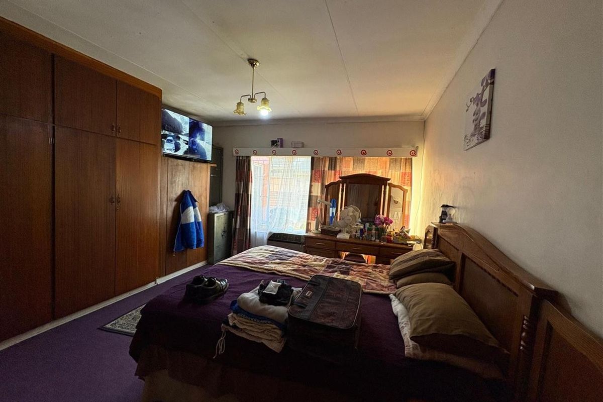 A spacious bedroom featuring extensive built-in wooden cabinetry and large windows that provide natural light.