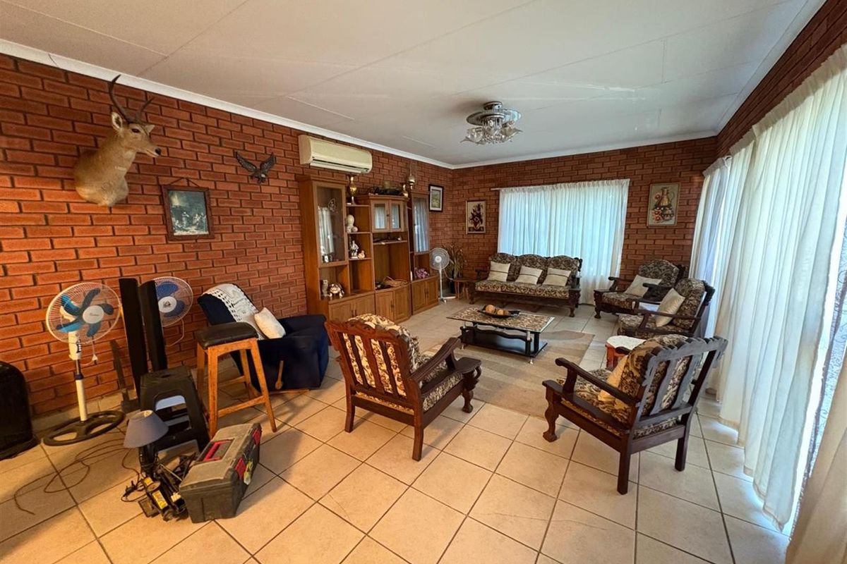 Spacious living room featuring exposed brick walls, tiled flooring, and a wall-mounted air conditioning unit.
