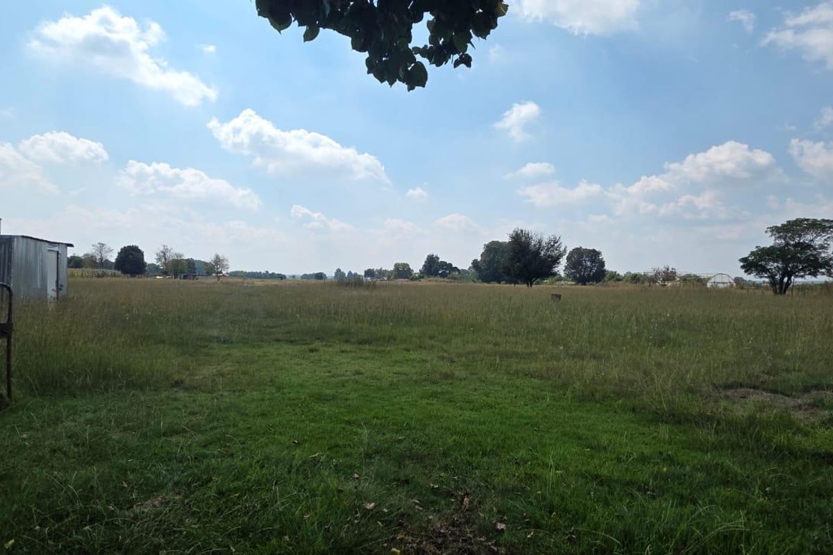 Expansive open farm land featuring a corrugated metal shed and perimeter fencing, offering significant space for agricultural or development potential.