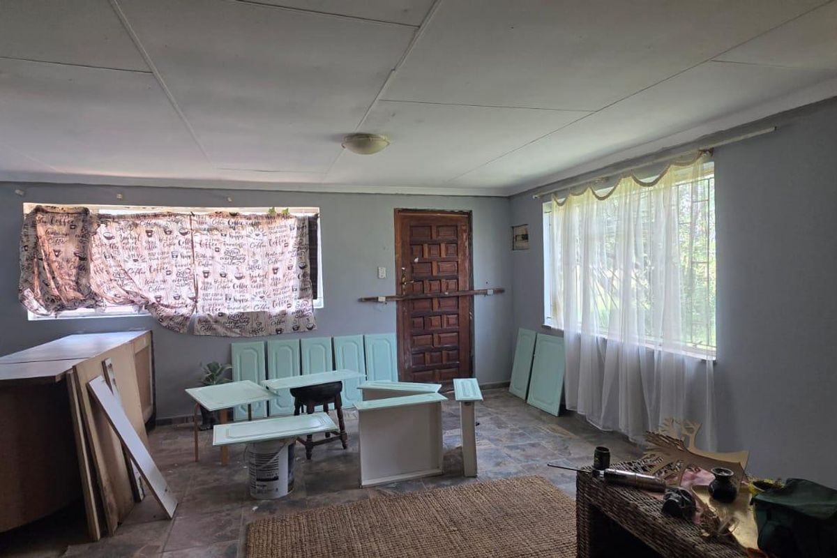 A living area currently undergoing renovation, featuring tiled floors, security bars on windows, and unfinished cabinetry components ready for installation.