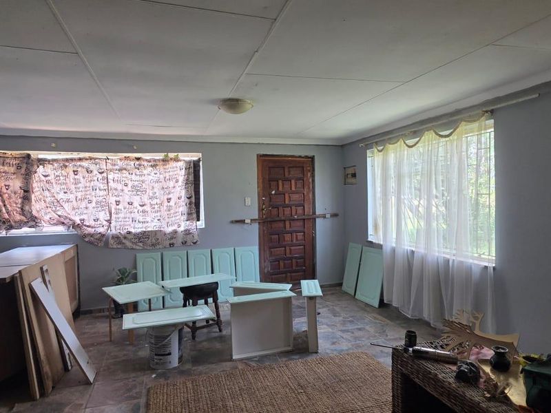 A living area currently undergoing renovation, featuring tiled floors, security bars on windows, and unfinished cabinetry components ready for installation.