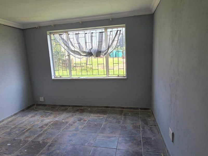 An empty bedroom featuring tiled flooring, grey painted walls, and security bars on the window.