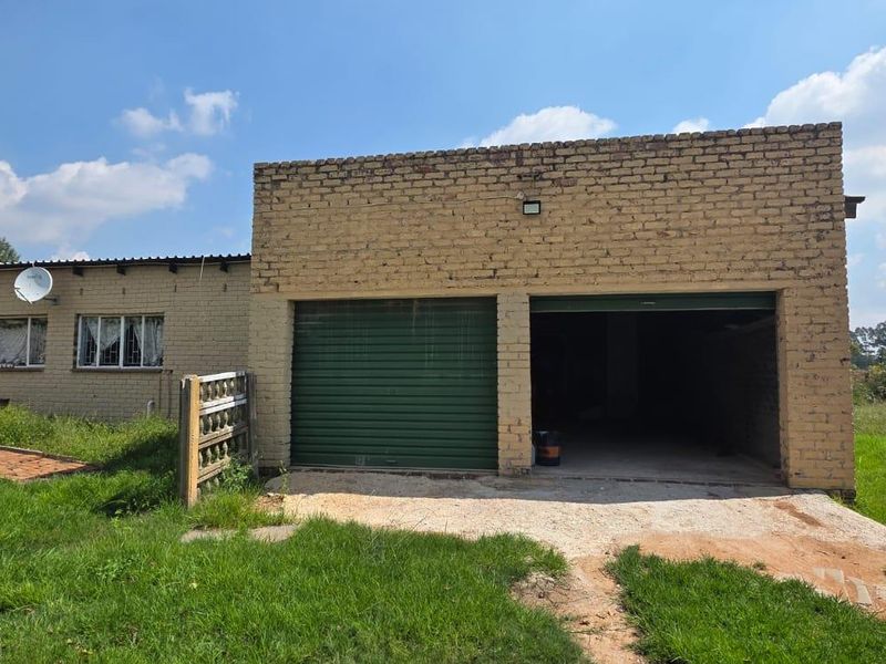 Front view of a farm-style property featuring a double garage with roller shutter doors and a brick exterior facade.