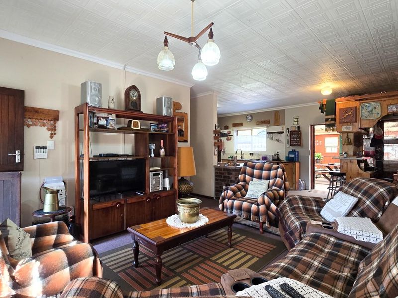 Spacious open-plan living area featuring a tiled ceiling and an adjoining kitchen with timber cabinetry and a brick island.