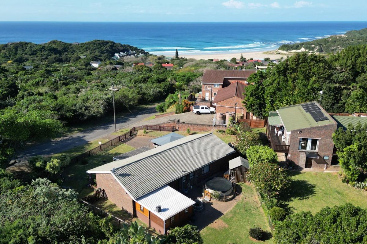 Aerial view of the property showing the main dwelling, surrounding garden, and proximity to the coastline and beach.