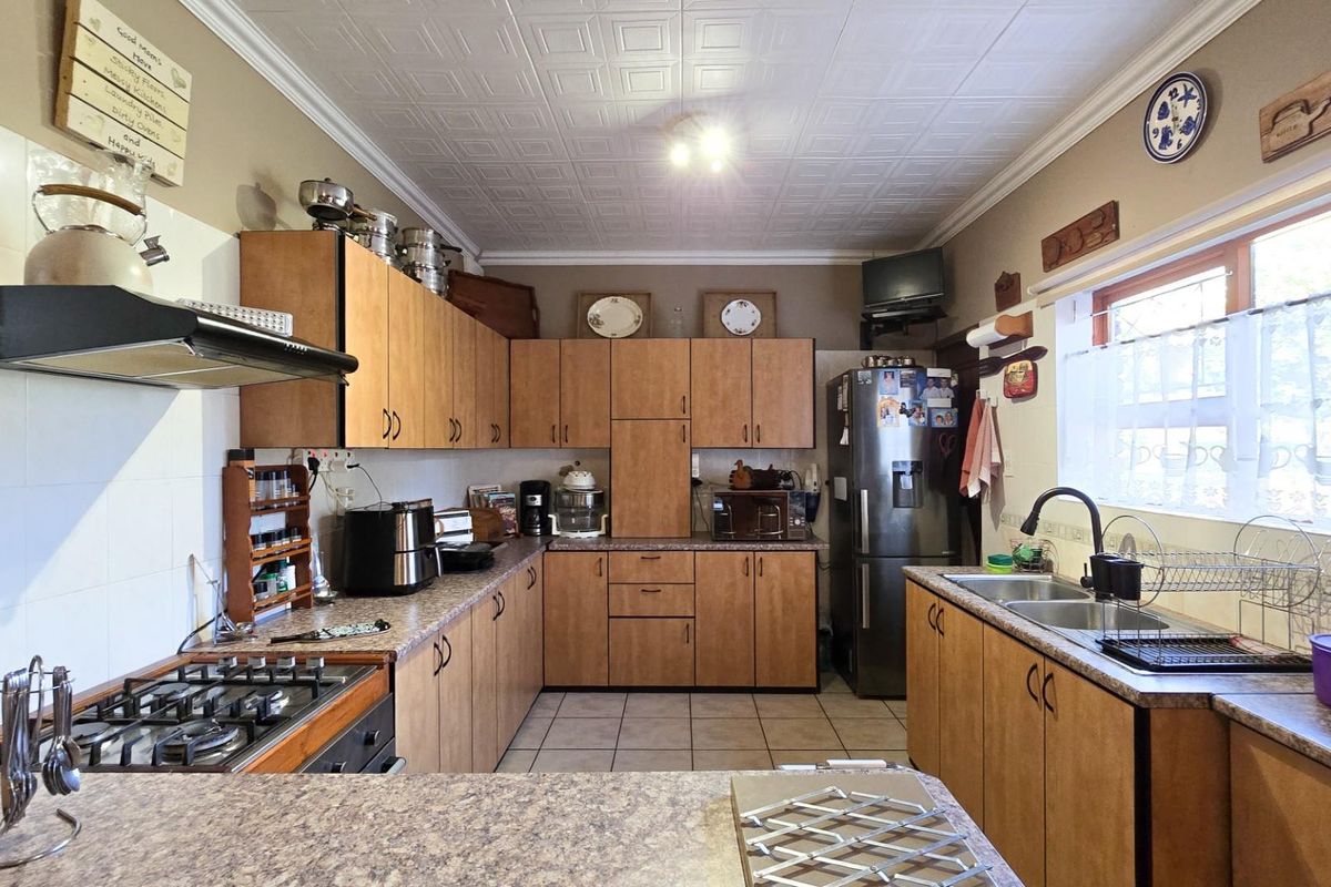 A functional kitchen featuring laminate cabinetry, gas hob with extractor fan, double bowl sink, and tiled flooring with a classic ceiling finish.