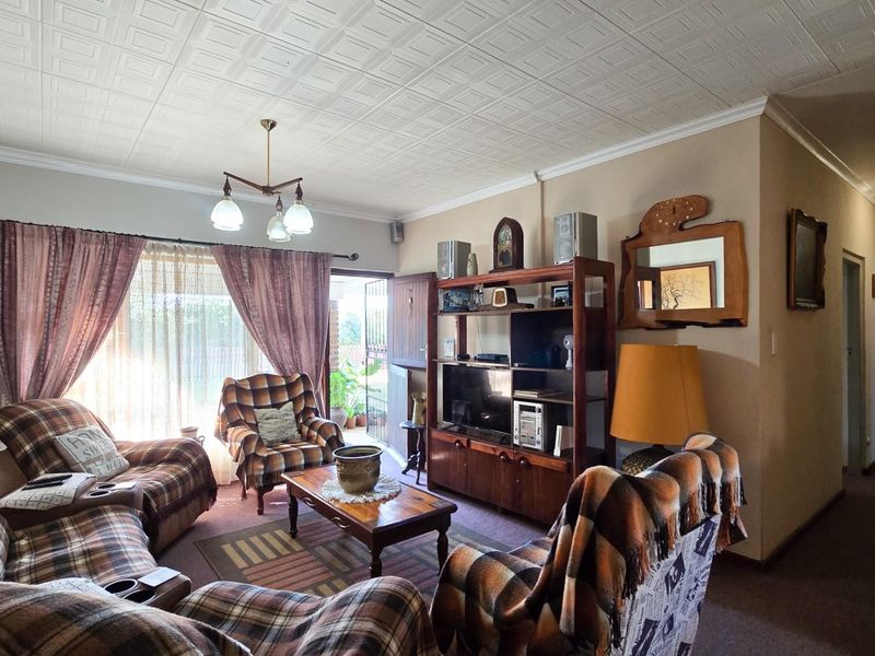 A living room featuring a coffered ceiling and a sliding glass door providing access to the exterior.