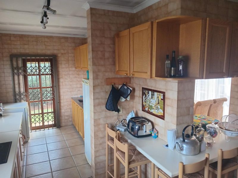 A dated kitchen featuring tiled walls, wooden cabinetry, and a breakfast counter, with direct access to the exterior through a security gate.