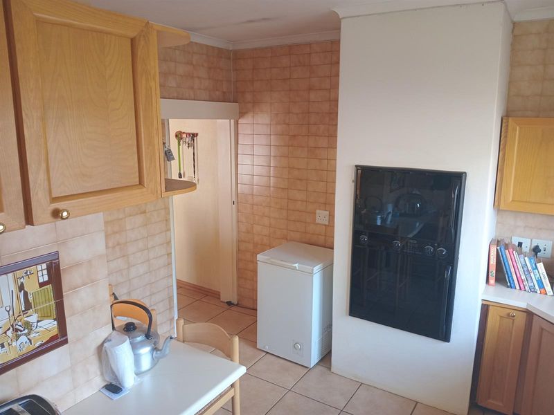 A functional kitchen featuring wooden cabinetry, tiled splashbacks, and a built-in oven, offering a classic layout with potential for modern updates.