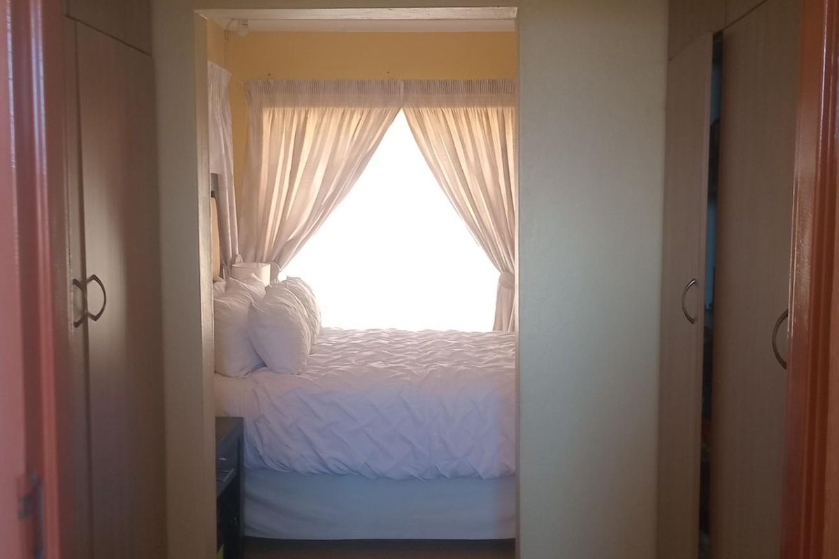 Bedroom featuring built-in cupboards and natural light, viewed from an adjacent hallway.