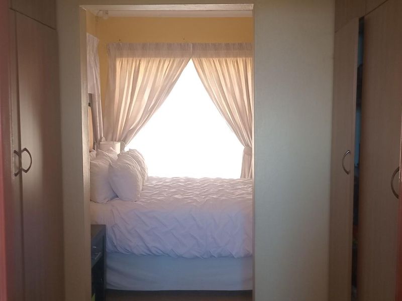 Bedroom featuring built-in cupboards and natural light, viewed from an adjacent hallway.