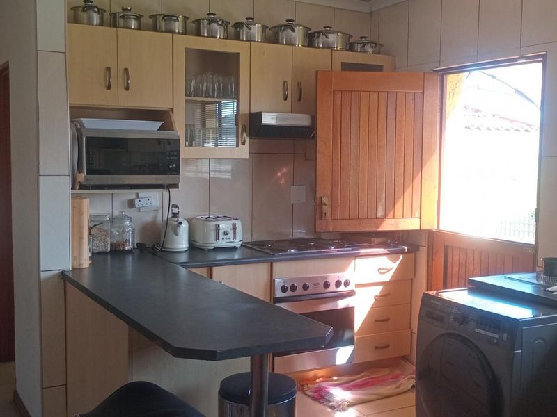 A functional kitchen featuring built-in cabinetry, laminate countertops, a built-in oven with hob, and tiled finishes, offering a practical layout for daily use.