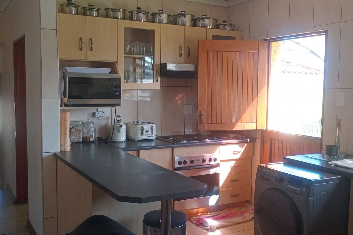 A functional kitchen featuring built-in cabinetry, laminate countertops, a built-in oven with hob, and tiled finishes, offering a practical layout for daily use.